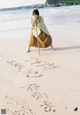 A woman standing on a beach holding a stick.