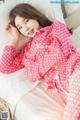 A woman laying on a bed in a pink polka dot pajamas.