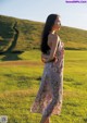 A woman standing in a field with her back to the camera.