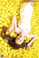 A woman laying in a pile of yellow lemons.