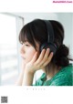 A young woman wearing headphones looking out a window.