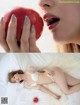 A woman laying on a bed holding an apple.