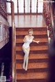 A woman in a white bodysuit is sitting on the stairs.