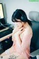 A woman sitting in front of a computer wearing headphones.