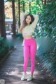 A woman in a white top and pink leggings posing for a picture.