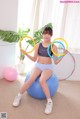 A woman sitting on an exercise ball holding a hula hoop.