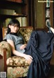 A woman sitting in a chair in front of a book shelf.