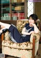 A woman sitting in a chair in front of a bookcase.